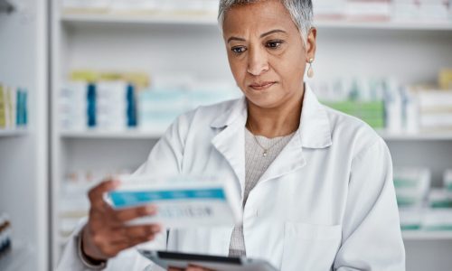 Pharmacist woman, tablet and reading box for information, stock or wellness in store with focus. Senior pharma expert, digital tech and stock in pharmacy for medicine, health or online help in Mumbai.