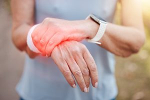 Woman, wrist pain and red injury on sports workout, wellness exercise and health training in forest. Zoom on hands, fitness strain and medical emergency or burnout accident in outdoor nature workout.