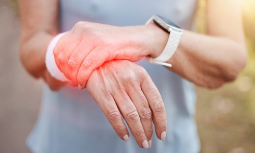 Woman, wrist pain and red injury on sports workout, wellness exercise and health training in forest. Zoom on hands, fitness strain and medical emergency or burnout accident in outdoor nature workout.
