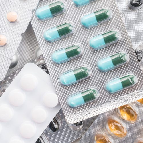 packings of pills and capsules of medicines on white background